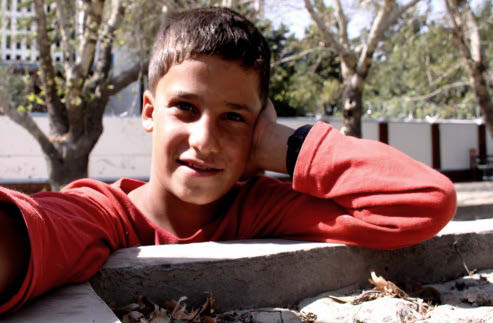 Young boy leaning against a wall